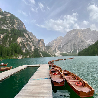 wooden boats and moorings with lake and mountains at Lago di Braies