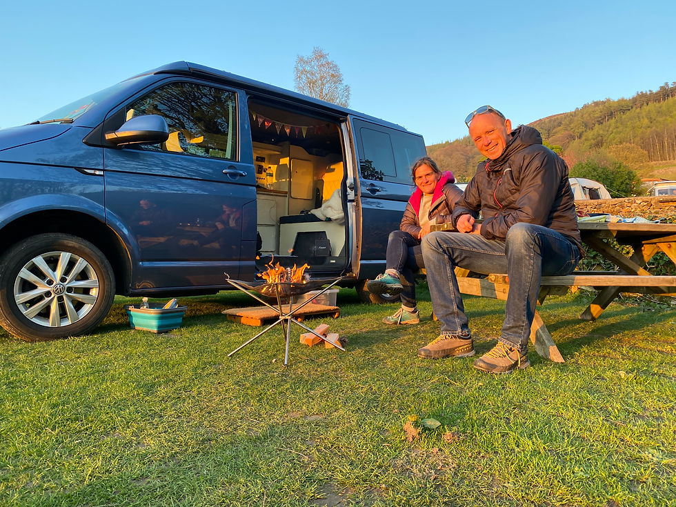 Couple sat outside campervan with open fire
