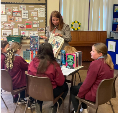 Teacher engaging Year 5 students with books in a classroom
