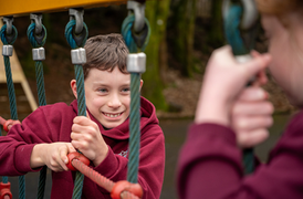 Young boy smiling while hanging from playground equipment, Year 5, Beaufort Hill