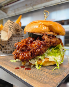 A fried chicken sandwich with a huge, crispy chicken breast with hot honey glaze