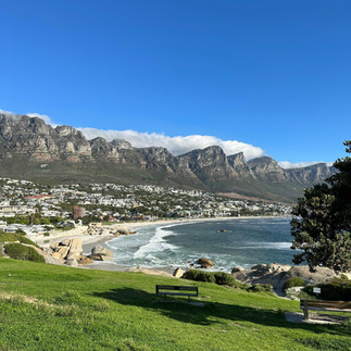 Camp’s Bay Cape Town’da deniz, kum ve güneşin tadını çıkarın! Arka planda Oniki Havariler Dağları manzarası eşliğinde plaj keyfi yapın, sahil restoranlarında yerel lezzetleri deneyimleyin