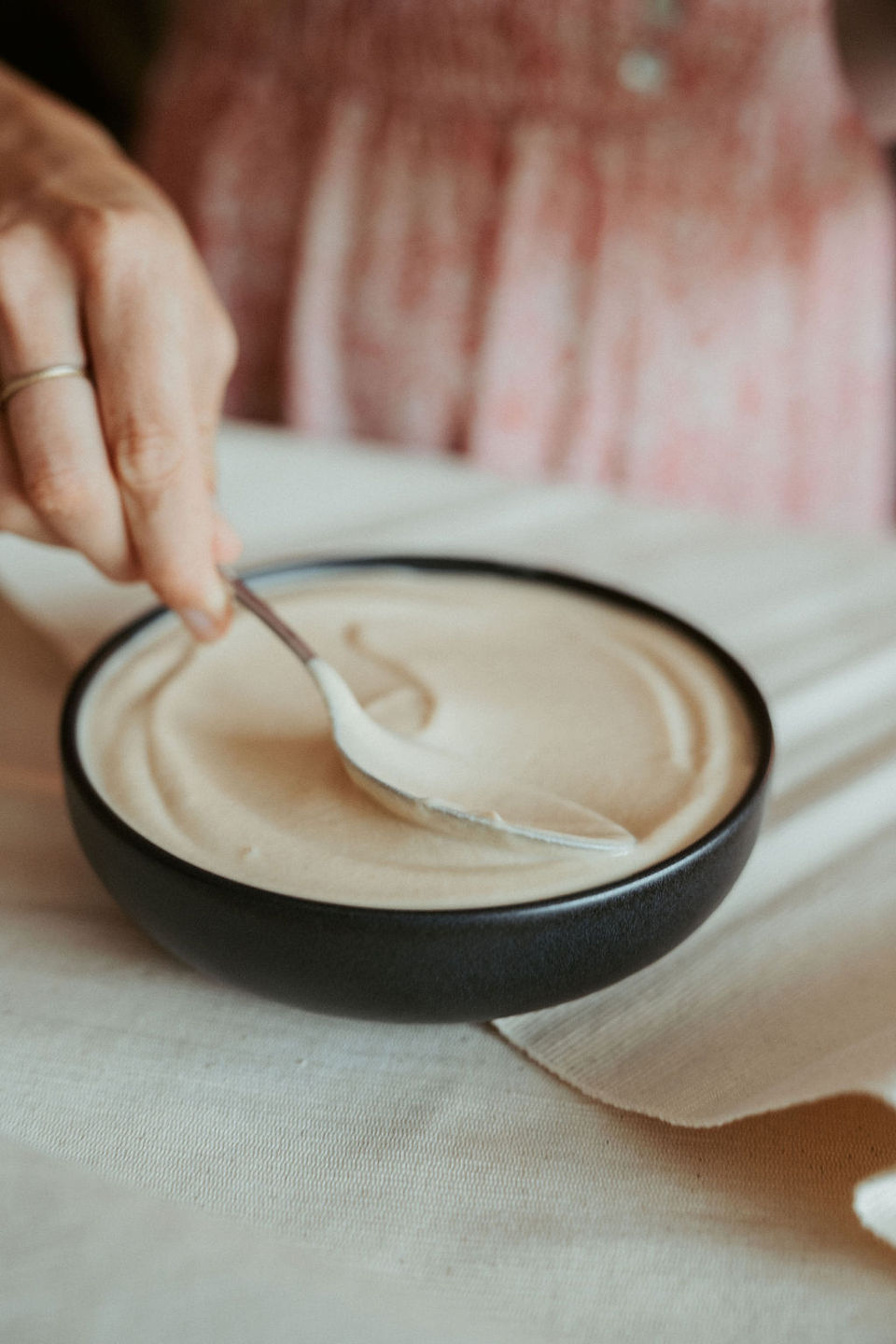 Creating a smooth, creamy texture in a bowl of homemade hummus with a spoon. 