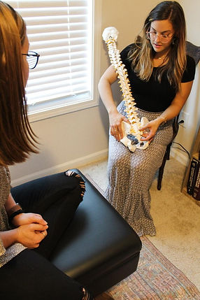 Dr. Alyssa explaining spine health with a model during a new patient's first-visit consultation