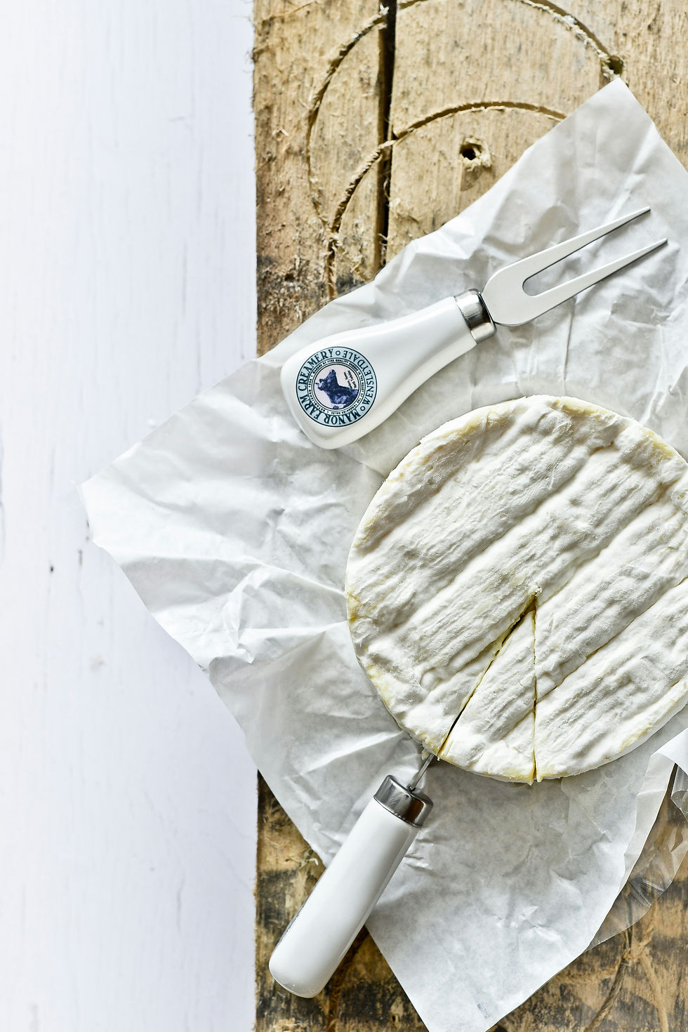 Camembert de Normandie frais avec ustensile de dégustation sur planche rustique - fromage français authentique en vente chez Franchutes