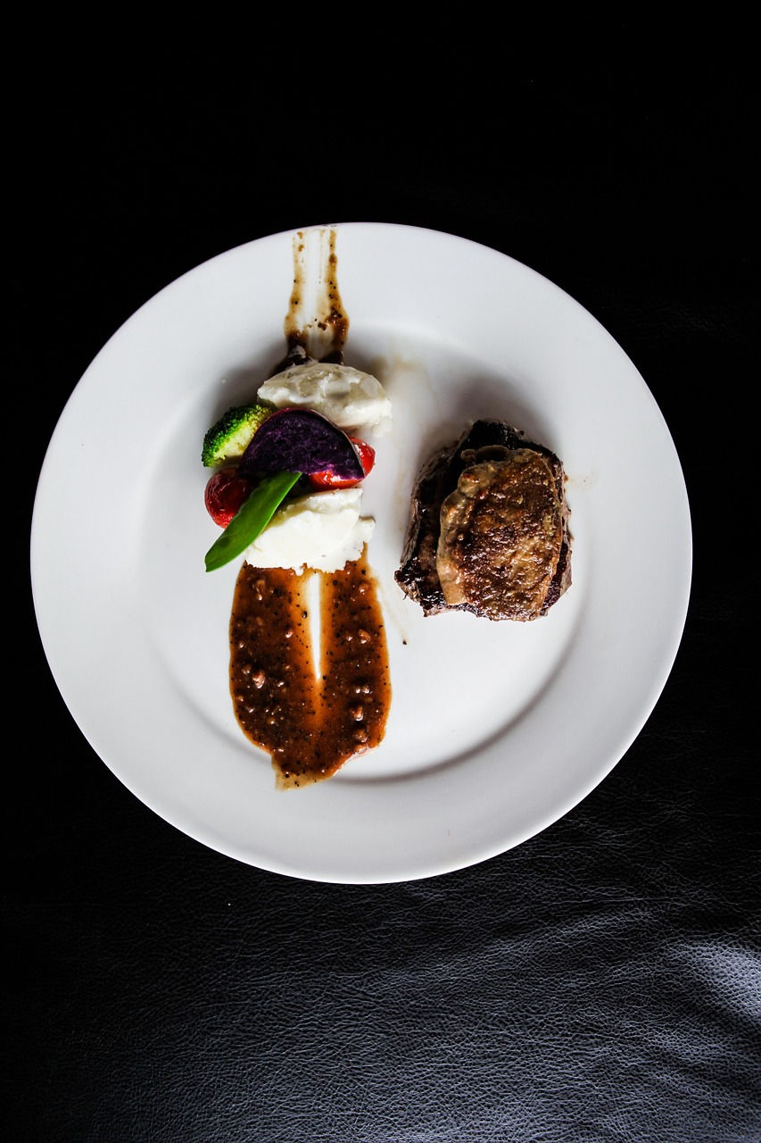 Foie gras mi-cuit au four sur lit de magret de canard avec sauce aux fruits rouges, accompagné de purée garnie de sauce à la carotte, dans une présentation gastronomique moderne.