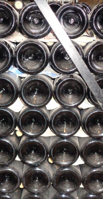 Rows of wine bottles aging in an underground cellar.