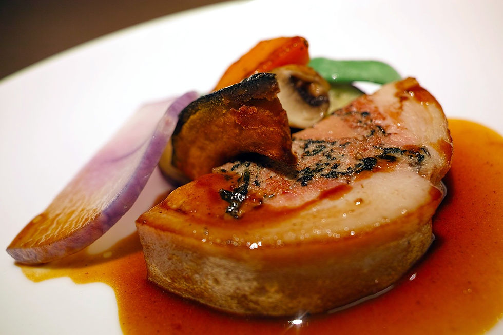 Tranche de foie gras mi-cuit au four accompagnée de légumes rôtis et nappée d’une sauce au vin, mettant en valeur les contrastes de textures et de couleurs dans une présentation gastronomique.