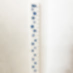 Hand-painted pale mid and dark blue stars scattered on white wooden growth chart
