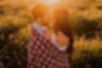 a couple on a morning date wrapped in a blanket in a field
