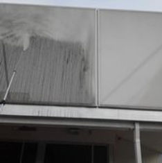 High-pressure power washing wand cleaning years of dirt and grime from a commercial building facade
