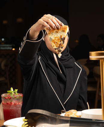Guest holding a slice of authentic Italian pizza at Arina Pizzeria in Qatif
