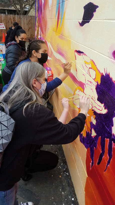 People painting a colorful community mural led by artist and muralist Jaya King in Sacramento.