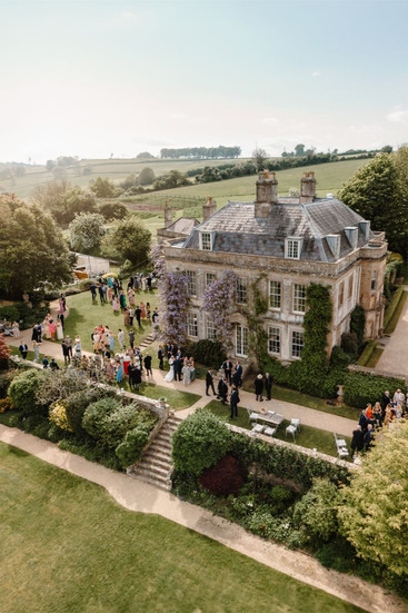 Aerial view of exclusive-use English country manor estate with wedding guests on manicured grounds