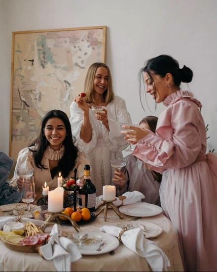 Women in elegant attire toasting and socialising at an intimate destination wedding dinner