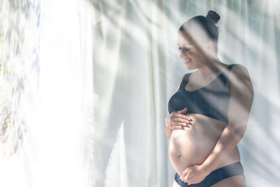 Mujer embarazada sonriendo de perfil mientras sostiene su vientre, iluminada por una luz natural suave, acompañada por el logotipo de Prenatal Life Test y la frase "Grandes alegrías".