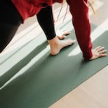 woman doing plank yoga pose on a green yoga mat
