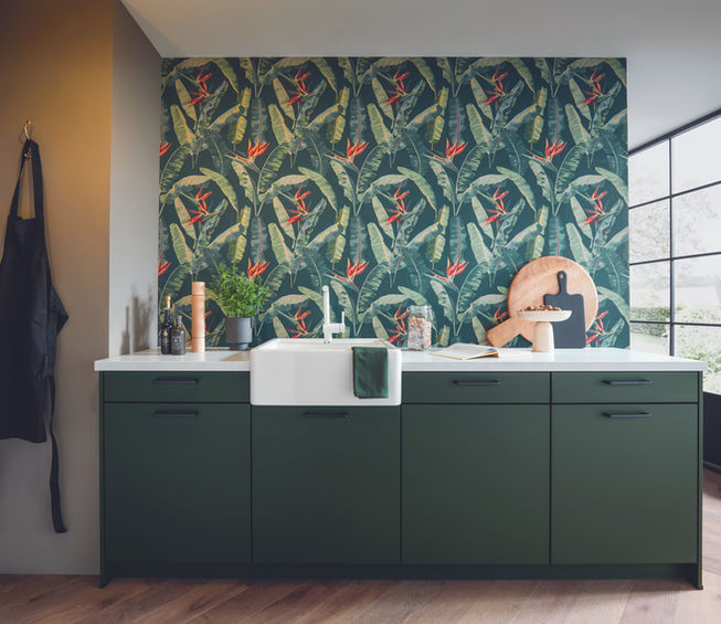 Belfast style sink with forest theme wallpaper and green cabinets in a Schuller kitchen.