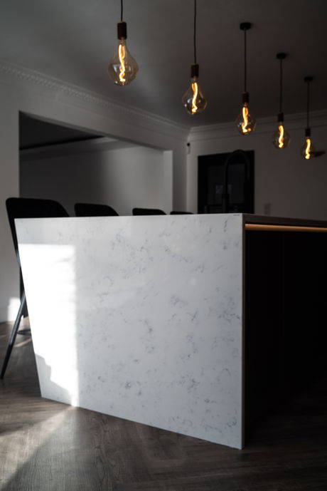 Angled white quartz side panel on Next125 platinum metallic island with LED emotion lighting in the griprail, under pendant lights in North East UK.  