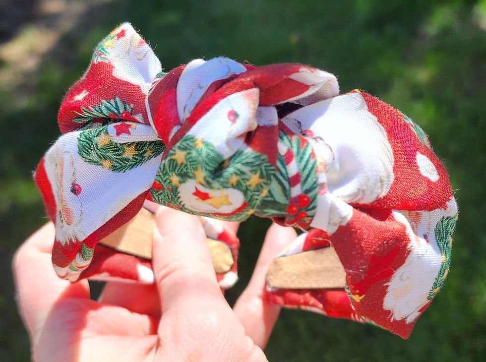 Hand holding a red fabric knotted headband with vintage-style Santa Claus and holiday print design