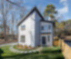 Modern two-story house with gray and white siding, with trees and lawn.