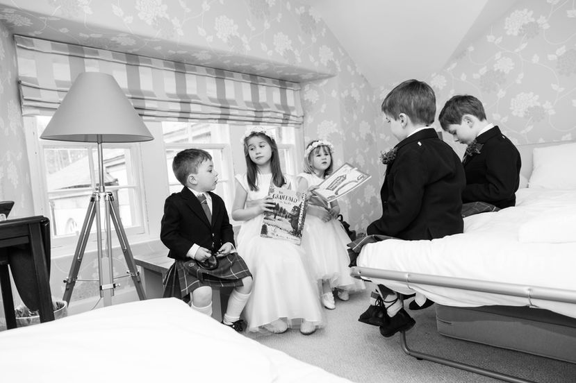 black and white photo of flower girls and paige boys sitting around reading a book