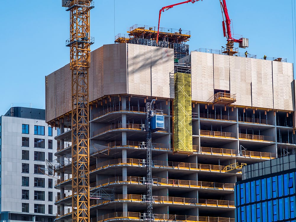 Construction commercial site with a building in progress. Two cranes are visible. The sky is clear blue, creating a vibrant urban setting.