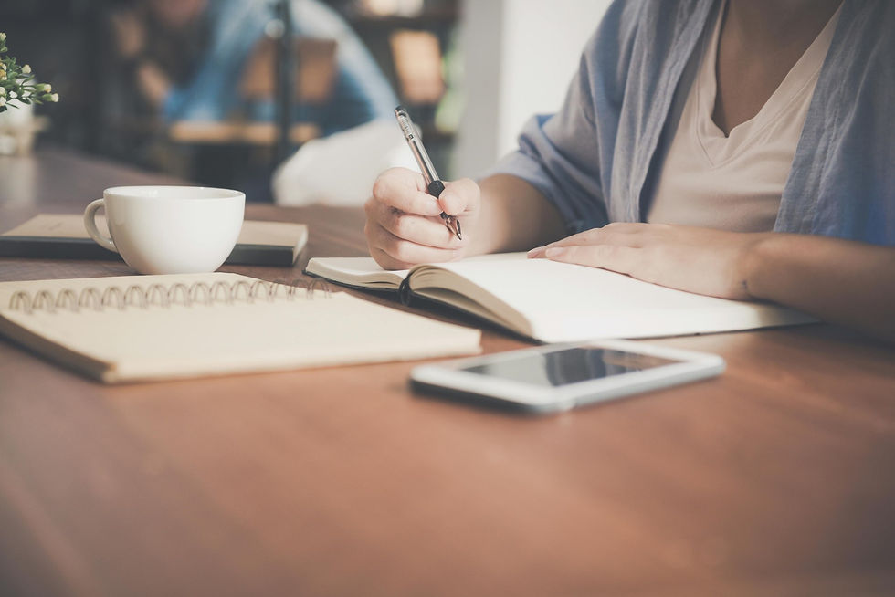 A woman writing in her journal at a coffee shop.