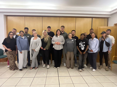 A group of expectant first time parents attend a Hello Baby antenatal class in Bushey. They are posing for a picture, standing in from of a wooden wall.