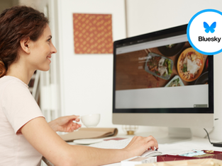 Woman using a desktop computer, adding the Bluesky logo to her website for seamless social media integration.