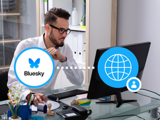 Man working at a computer with Bluesky logo connected to a website, representing social media integration for businesses in 2025.