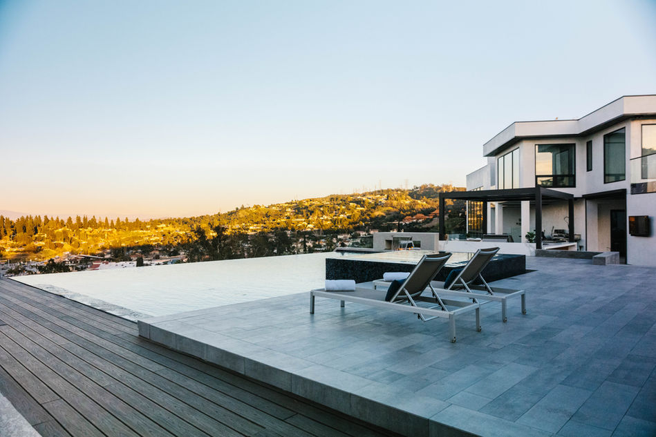 A luxurious infinity pool at a modern hillside estate in Palos Verdes, CA, featuring sleek lounge chairs, expansive views, and contemporary architecture designed by Leli Construction.