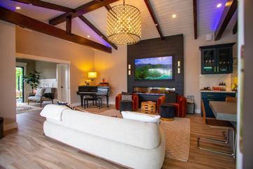 Luxury living room with exposed beams, custom fireplace, modern furnishings, and vibrant accents, designed by Leli Construction in Orange County