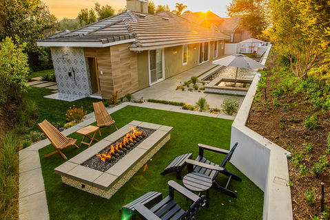 Custom backyard with modern firepit, outdoor shower, pool, and lush landscaping designed by Leli Construction in Southern California.