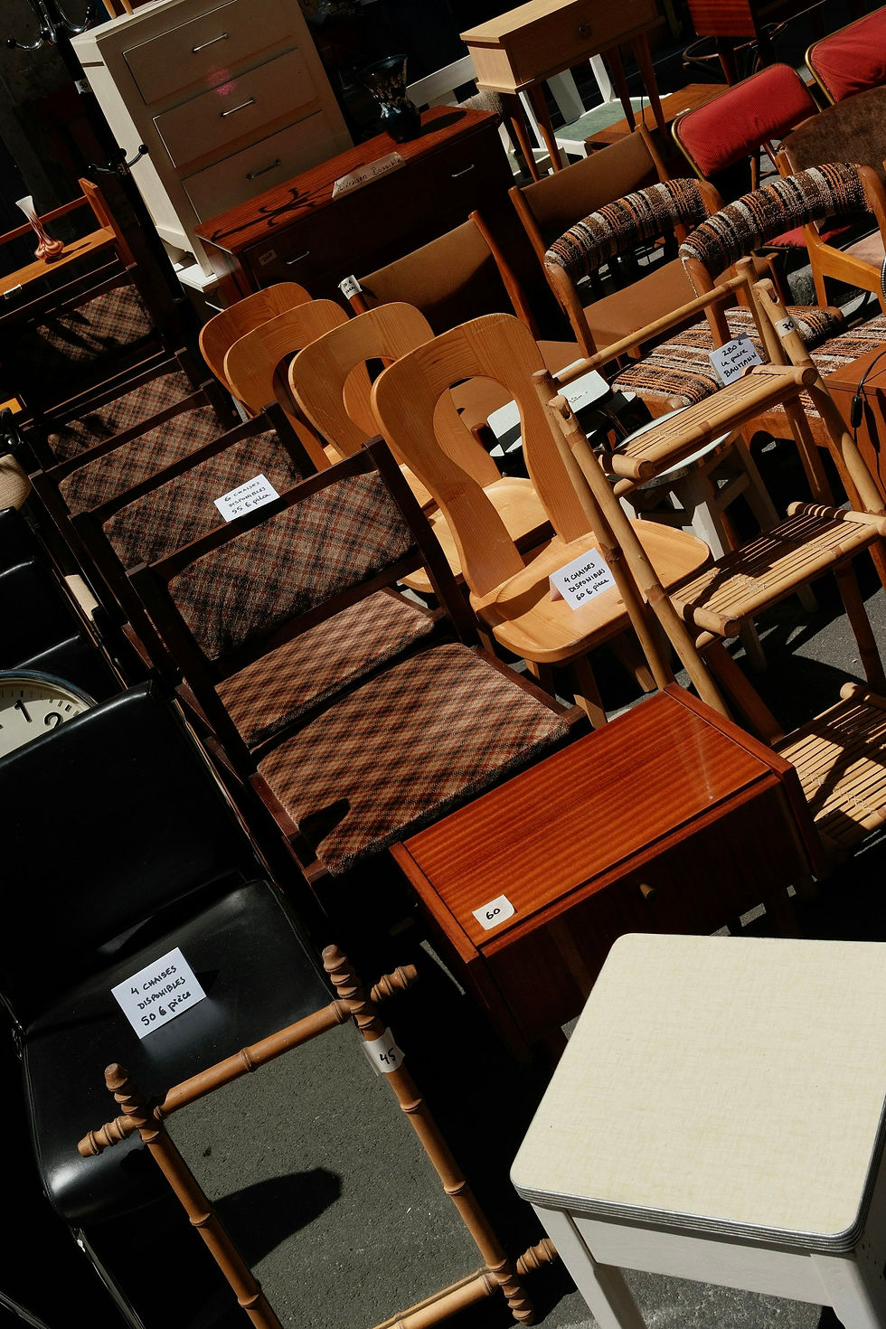 Rijen gebruikte stoelen en bijzettafels te koop op straat
