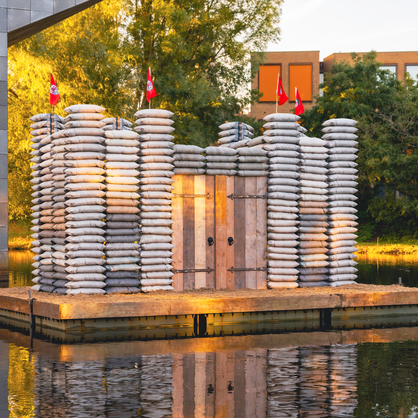 Kasteel van gestapelde betonnen zandzakken op een vlot in het water, in avondlicht