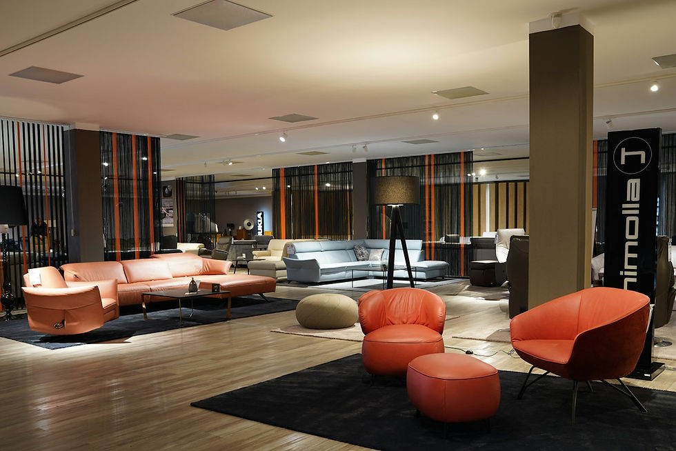 Showroom met oranje fauteuils, een lichte bank en vloerkleden onder sfeerverlichting