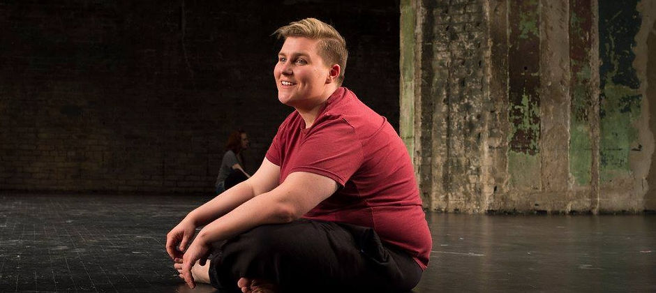 Allison Vincent sitting cross legged on The Southern Theater's stage with Emily Dussault in the back