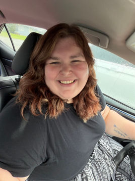 a woman with red-blonde hair smiles in a parked car