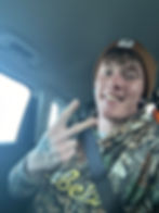 Man in car smiling, making peace sign