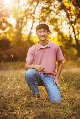 Senior FFA member poses in front of trees during golden hour for his senior portraits