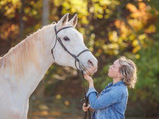 A owner poses with her white Arabian horse in a senior horse photoshoot
