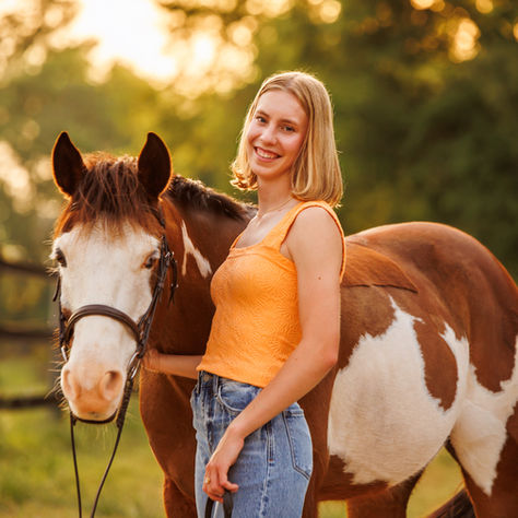 A senior girl poses with her paint horse in an equestrian senior portrait outside of Athens, GA