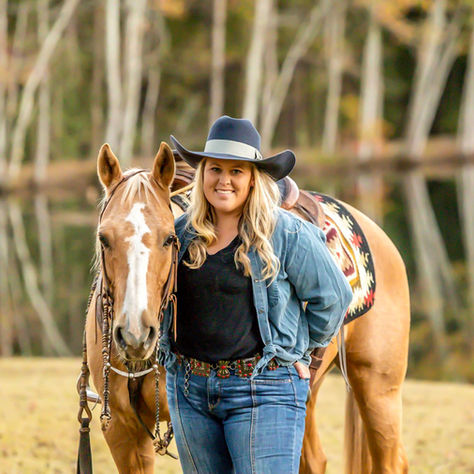A woman in a fall horse and rider portrait photoshoot with her palomino horse