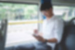 man sitting in a bus or van looking at his phone in his hand