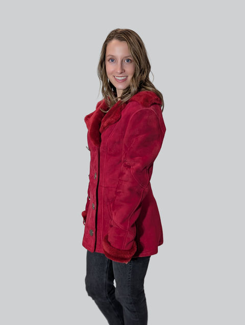 Woman wearing a red fur coat smiling at the camera.