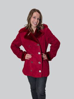 Smiling woman wearing red fur winter coat, hands on hips.