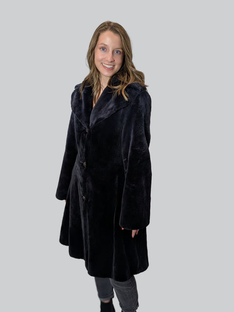 Woman wearing a black coat, smiling.