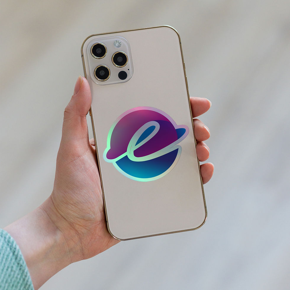 Hand holding a white smartphone with a holographic Elemental Essentials logo sticker on the back, against a blurred indoor background.
