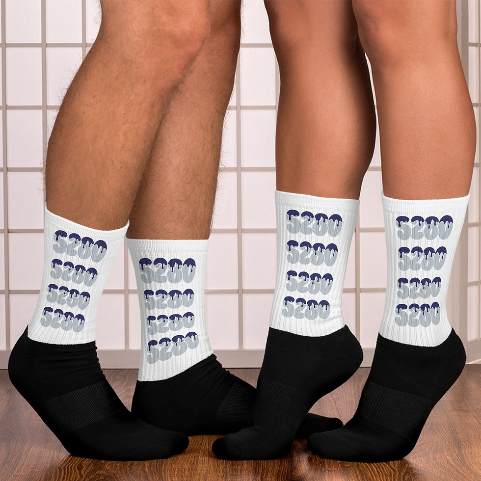 Two people wearing white and black socks with the Denver baseball-inspired "5280" design in shades of blue, paired with black feet, standing on a wooden floor against a tiled background.